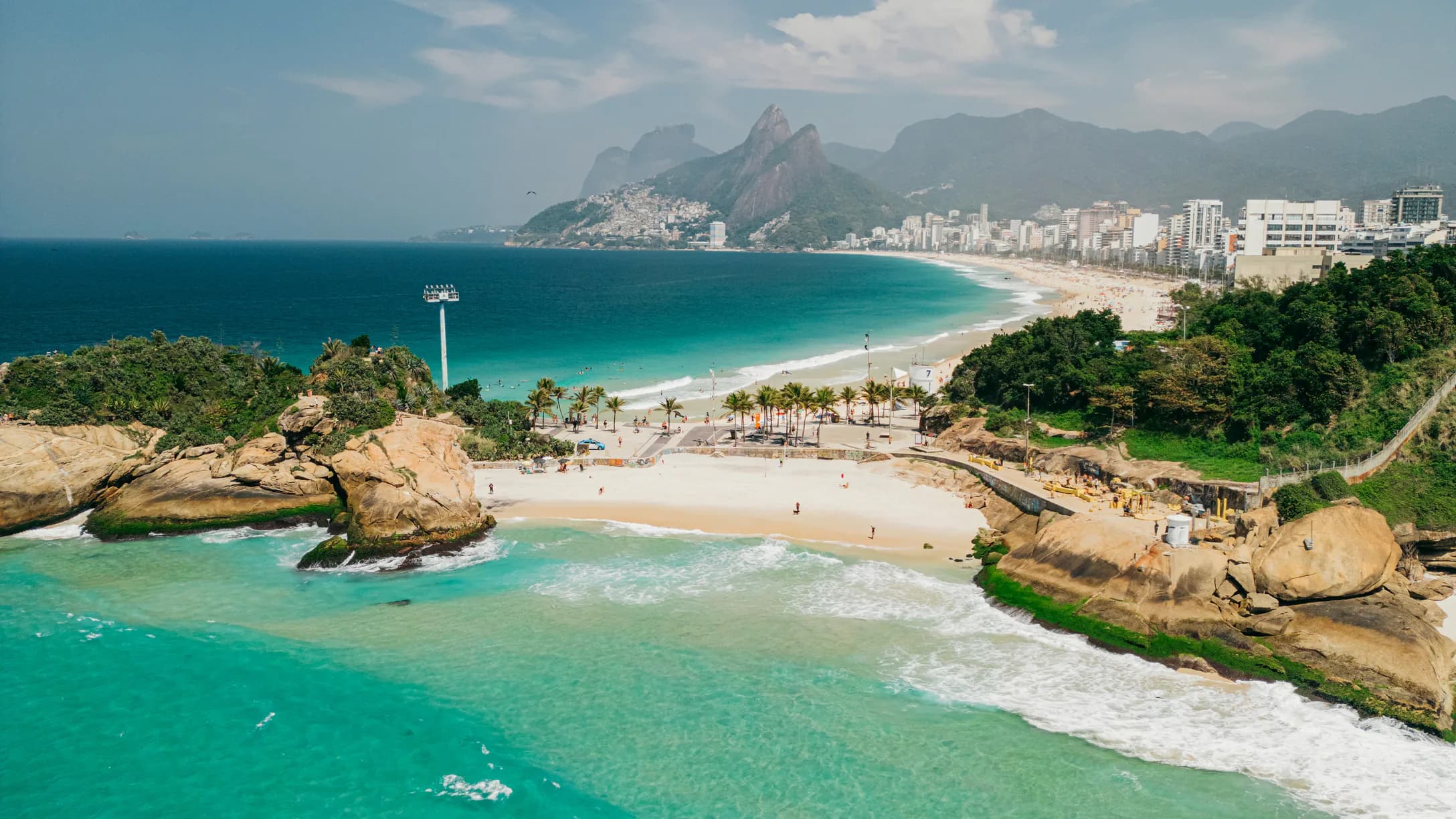 Vista aérea de Arpoador: rocas, una playa chica y, detrás, la playa de Ipanema con el morro Dois Irmãos